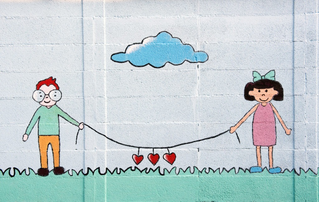 Wall mural of two young children holding a string with hanging hearts symbolic of love